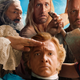 A group shot of the pirate cast of Our Flag Means Death, with Stede Bonnet (Rhys Darby) saluting at the center.